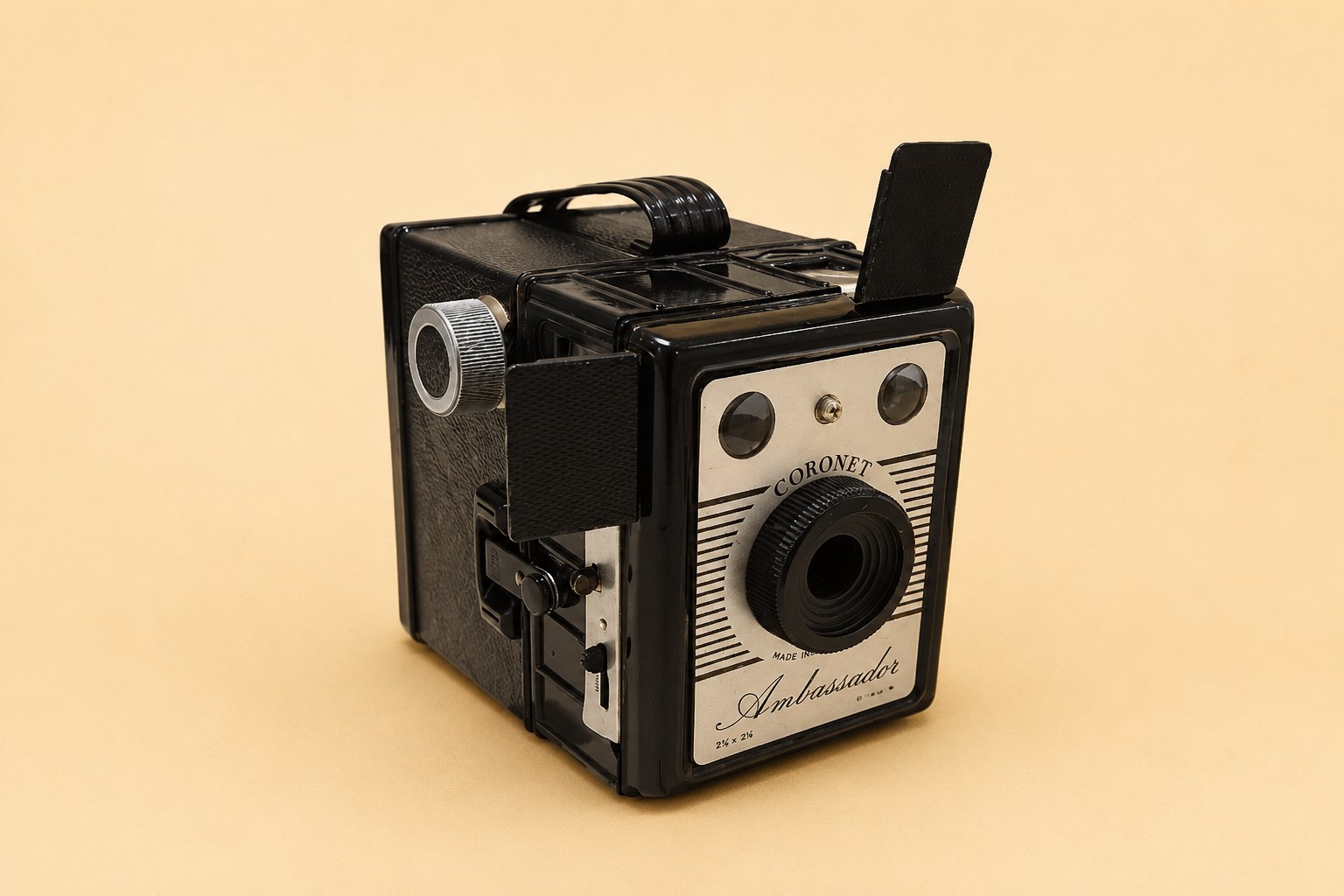 A black Coronet Ambassador box camera, Made in England, with a ribbed body, chrome-covered brilliant finders and a decorative metal front plate reading 'Coronet Ambassador, 6x9 cm'; shown from front, side and base (with a red 'Coro-Flash' label and serial H 62317), together with its printed 'Instructions for using the Box Camera' booklet.